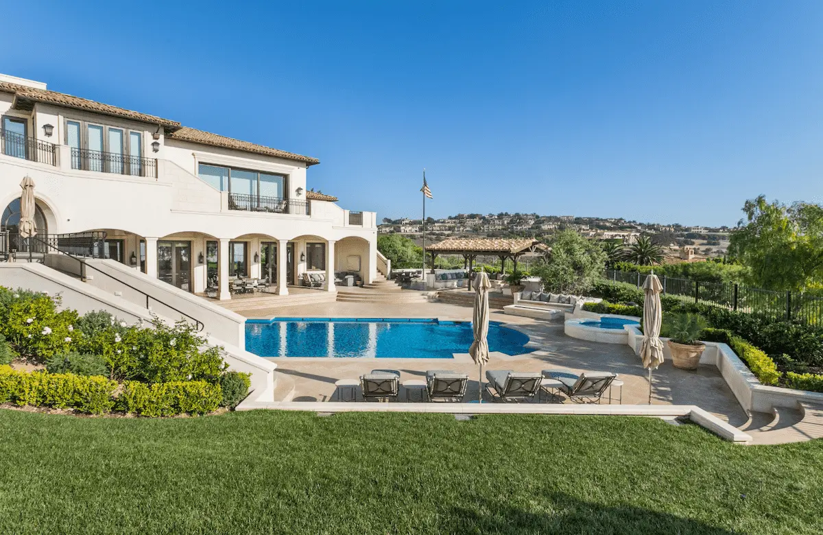 Pelican Hill home overlooking a pool terrace, lawn and landscaped grounds