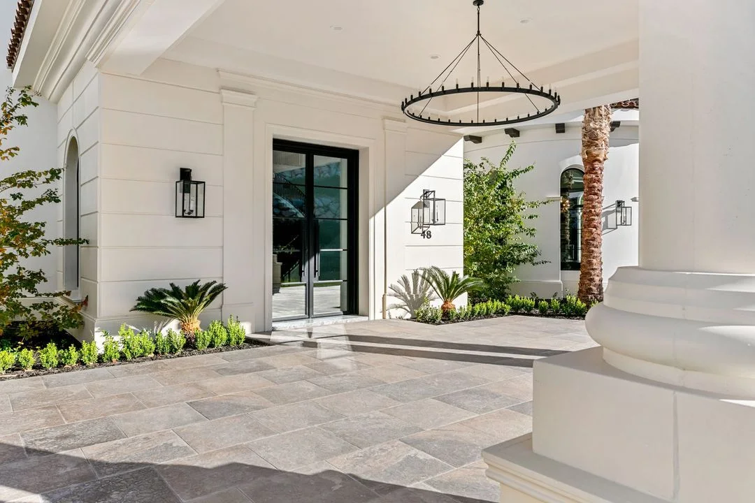 Covered terrace with pale paving and planted borders